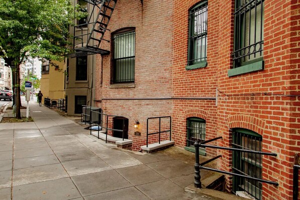 A narrow urban street with red brick buildings, a fire escape, and a sidewalk. - A Classy Corner of DC near Dupont Circle (Washington)