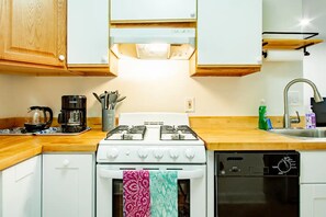 A kitchen with white cabinets, a stove, a coffee maker, and a dishwasher. - A Classy Corner of DC near Dupont Circle (Washington)