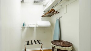 A laundry area with a drying rack, a basket, and a shelf with folded towels and an iron. - A Classy Corner of DC near Dupont Circle (Washington)