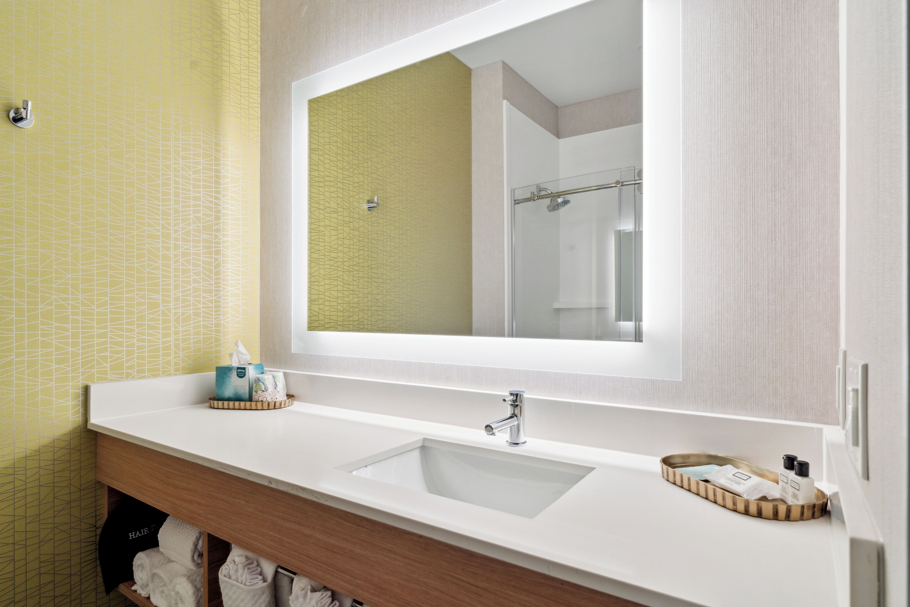 A bathroom with a white sink, a mirror, and a towel rack.