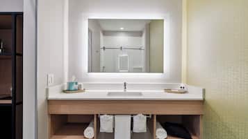 Un baño moderno con un espejo grande, dos lavamanos y estantes de madera debajo.