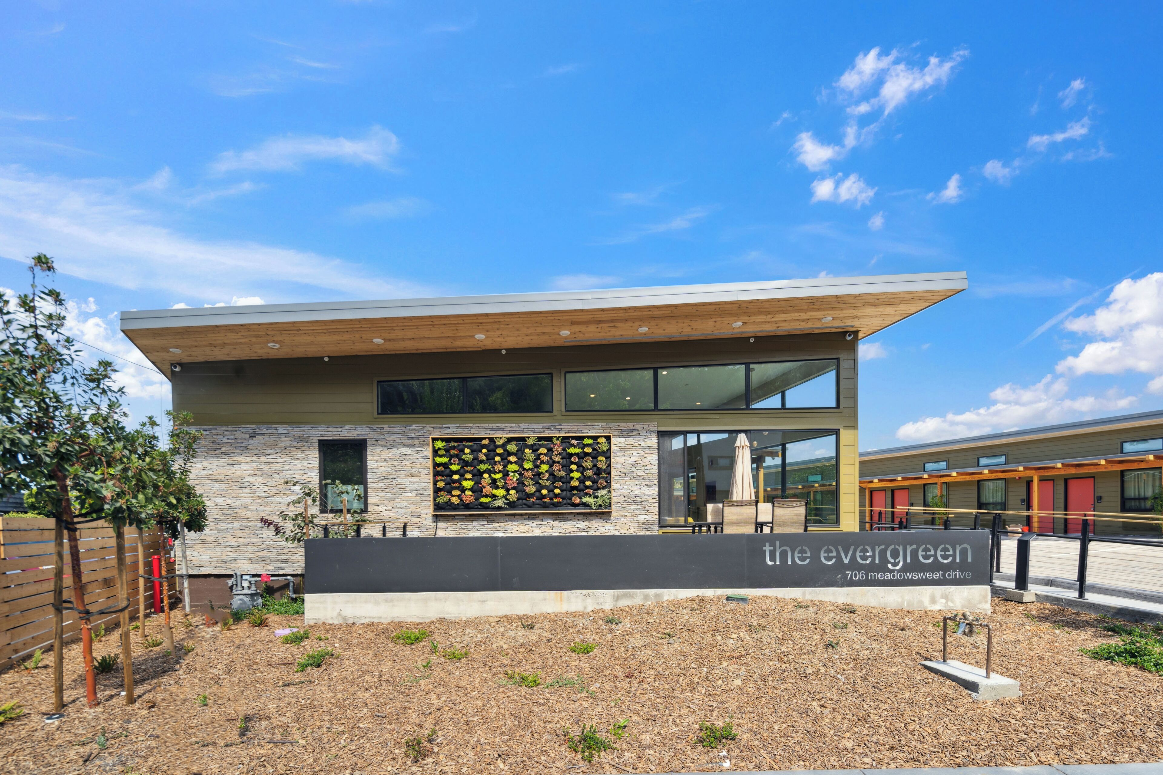 A modern building with a stone facade, large windows, and a sign reading "the evergreen."