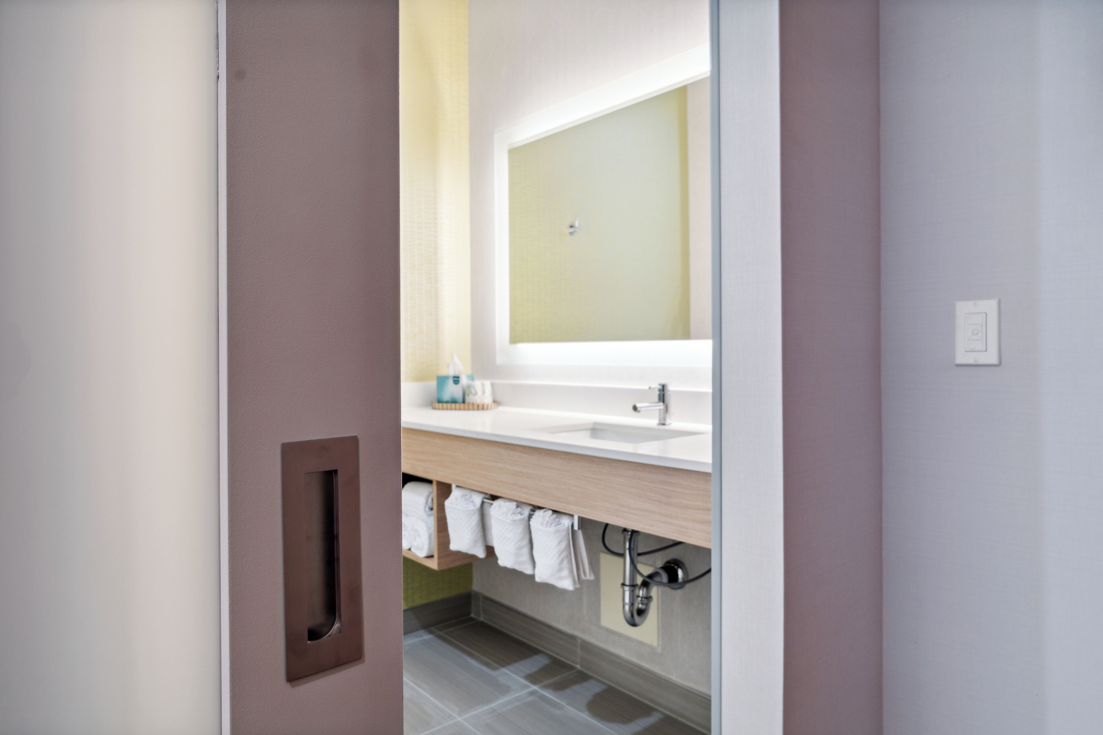 A modern bathroom with a large mirror, a sink, and a towel rack.