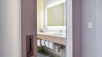 A modern bathroom with a large mirror, a sink, and a towel rack.