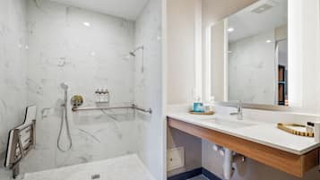 A modern bathroom with a marble shower, a sink with a wooden vanity, and a large mirror.