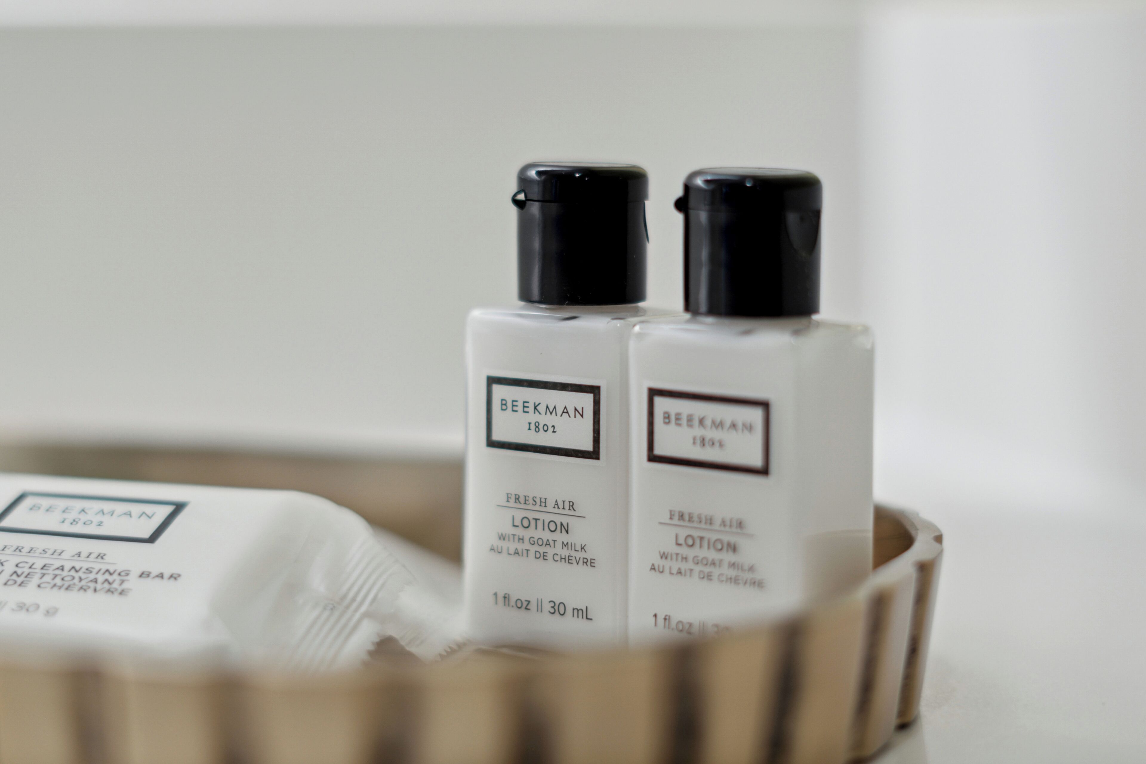 Two bottles of Beekman 1802 Fresh Air Lotion in a wooden container.