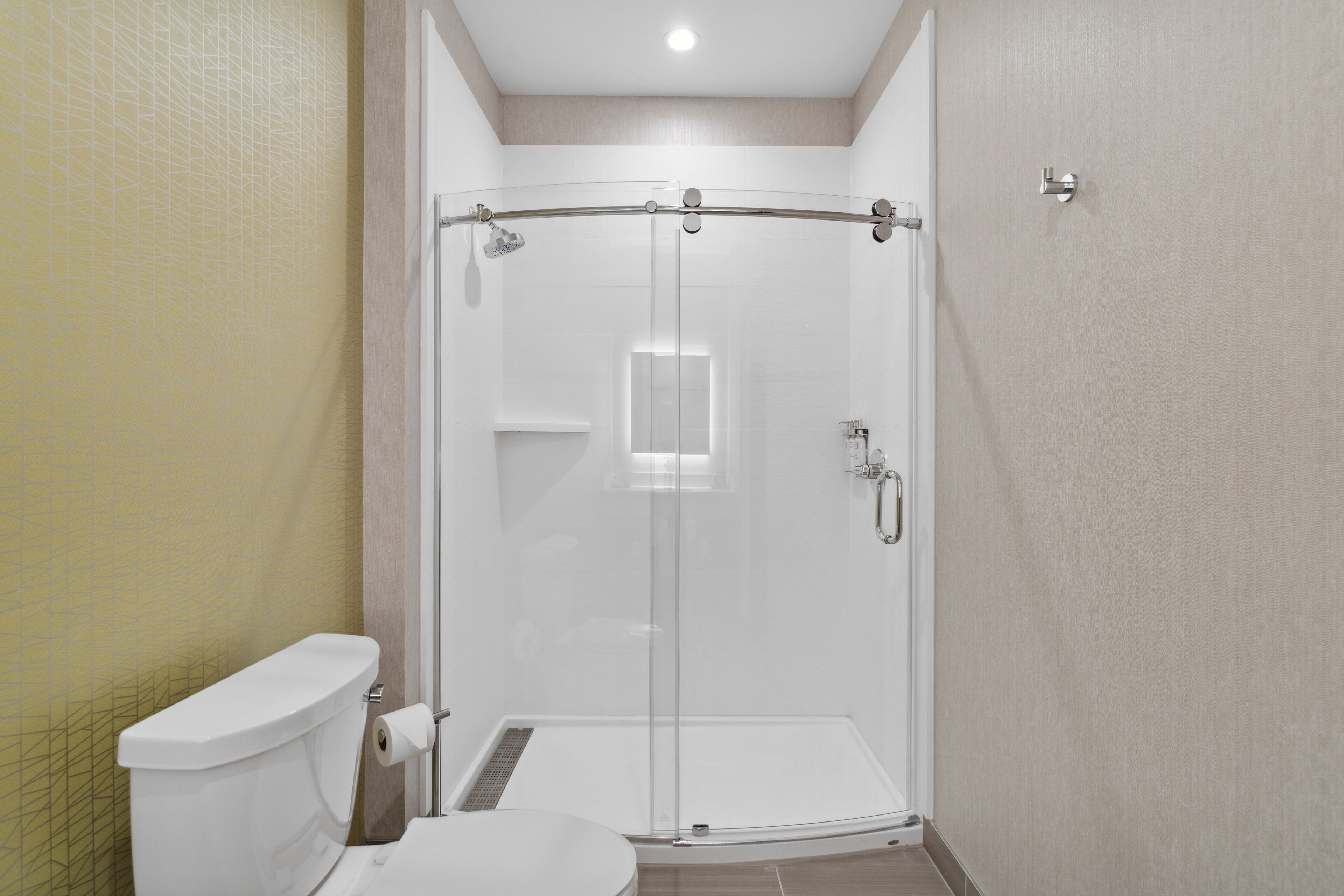 A modern bathroom with a glass-enclosed shower, a toilet, and a sink.