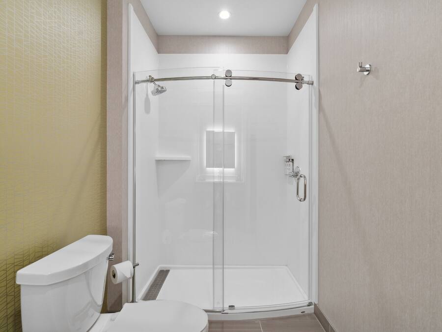 A modern bathroom with a glass-enclosed shower, a toilet, and a sink.