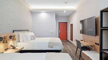 Ein modernes Hotelzimmer mit einem großen Bett, Nachttischen, einem Schreibtisch, einem Sessel, einem Fernseher und einer roten Tür im Hintergrund.