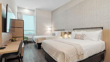 Ett modernt hotellrum med två sängar, ett skrivbord och en TV.