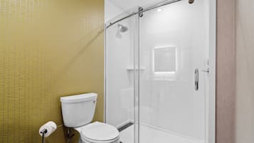 A bathroom with a toilet, a glass-enclosed shower, and a yellow patterned wall.