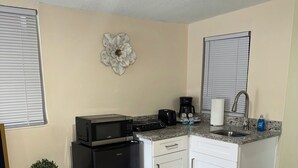 A compact kitchenette with a microwave, toaster, coffee maker, and sink. - Welcome to our charming studio, perfectly located near Tampa Bay's attractions. (Tampa)