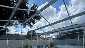 A covered swimming pool with a brick border, surrounded by chairs and potted plants. - Welcome to our charming studio, perfectly located near Tampa Bay's attractions. (Tampa)