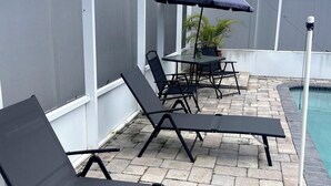 A patio area with black lounge chairs, a table, and an umbrella. - Welcome to our charming studio, perfectly located near Tampa Bay's attractions. (Tampa)