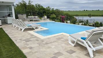A swimming pool with lounge chairs, a covered patio area, and a view of a lake.