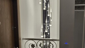 Un interior moderno con una puerta de madera, barandilla decorativa de metal y una lámpara en el techo.
