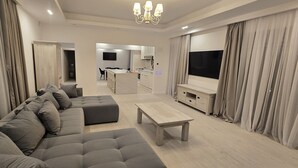 Una sala de estar moderna con un sofá seccional gris, una mesa de centro de madera y un televisor en la pared.