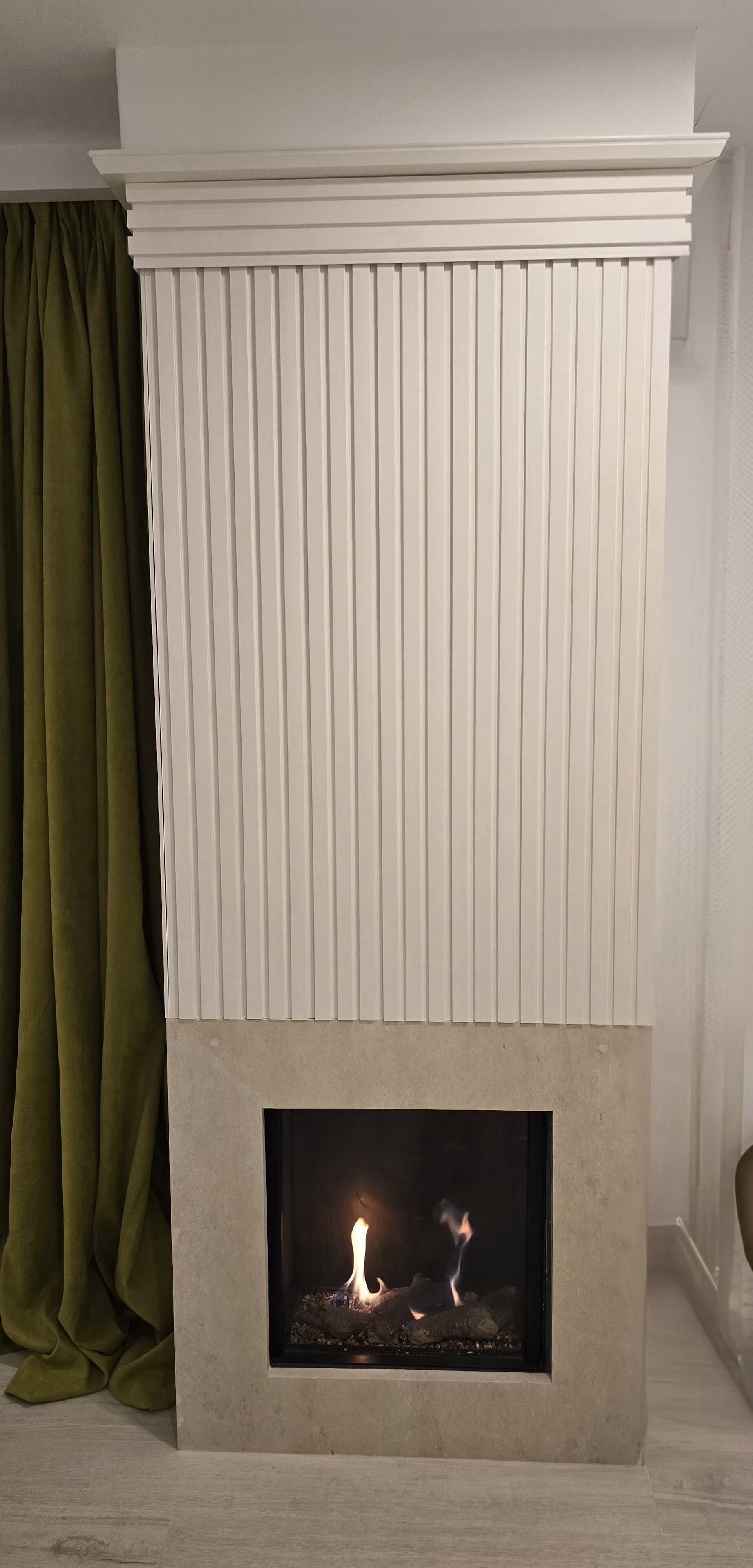 Une cheminée au design moderne, une manteau de cheminée avec des lattes verticales, et un feu qui crépite à l’intérieur.