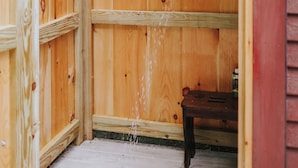 A wooden outdoor shower enclosure with a wooden bench inside. - Historic farmhouse by the river in Keene, NY near Lake Placid & Whiteface Mt. (Keene)