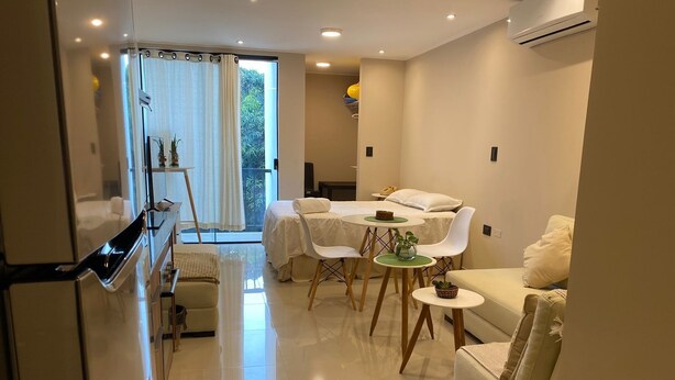 Un salon moderne avec un canapé, une table à manger et des chaises, ainsi qu’un lit doté d’un baldaquin blanc.
