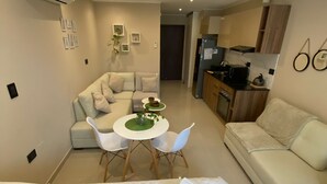 Une pièce moderne et bien éclairée, comprenant un lit, un canapé, une table à manger avec des chaises et un coin cuisine.