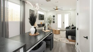 Una sala de estar moderna con un sofá gris oscuro, una mesa de centro redonda y un televisor montado en la pared.