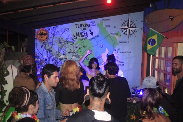 A group of people at a social event with a map and Brazilian flag in the background. - Off Ocean Hostel (Florianópolis)