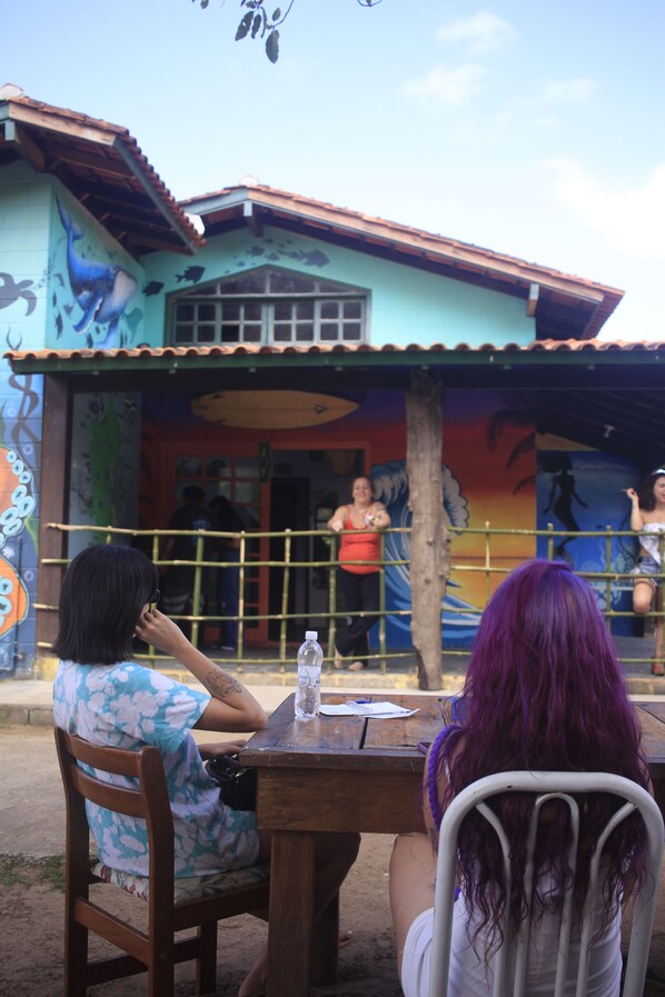 A dining area with a wooden table and chairs, a mural on the wall, and a building with a tiled roof.