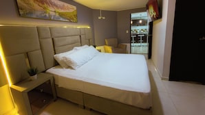 A modern bedroom with a large bed, bedside tables, a chair, and a painting on the wall. - SPACIOUS AND LUXURIOUS APARTASUITE IN THE CENTER OF THE CITY (Cartago)
