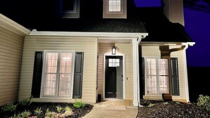 Una casa de dos pisos con porche delantero, un pequeño garaje adjunto y una chimenea.