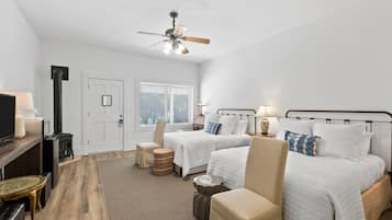 Une chambre d’hôtel avec deux lits, un ventilateur de plafond, une cheminée, une télévision et une fenêtre avec des stores.