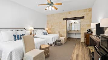 Une chambre d’hôtel avec deux lits, un ventilateur de plafond, une salle de bain avec un miroir et une télévision.