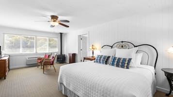 Une chambre avec un grand lit, un ventilateur de plafond, un radiateur, une fenêtre avec des stores et une chaise.