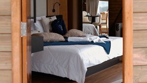 Ein Schlafzimmer mit einem Bett, einem Spiegel, einem Sessel und einer Holzzahl.