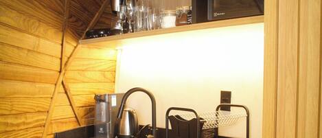 Una cocina compacta con techo de madera, cafetera, hervidor y microondas.