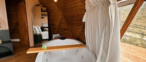 Un interior de madera con una bañera grande, vigas de madera e lámparas colgantes.