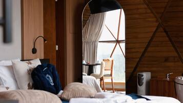 A bedroom with a bed, a desk, a chair, and a window with curtains.