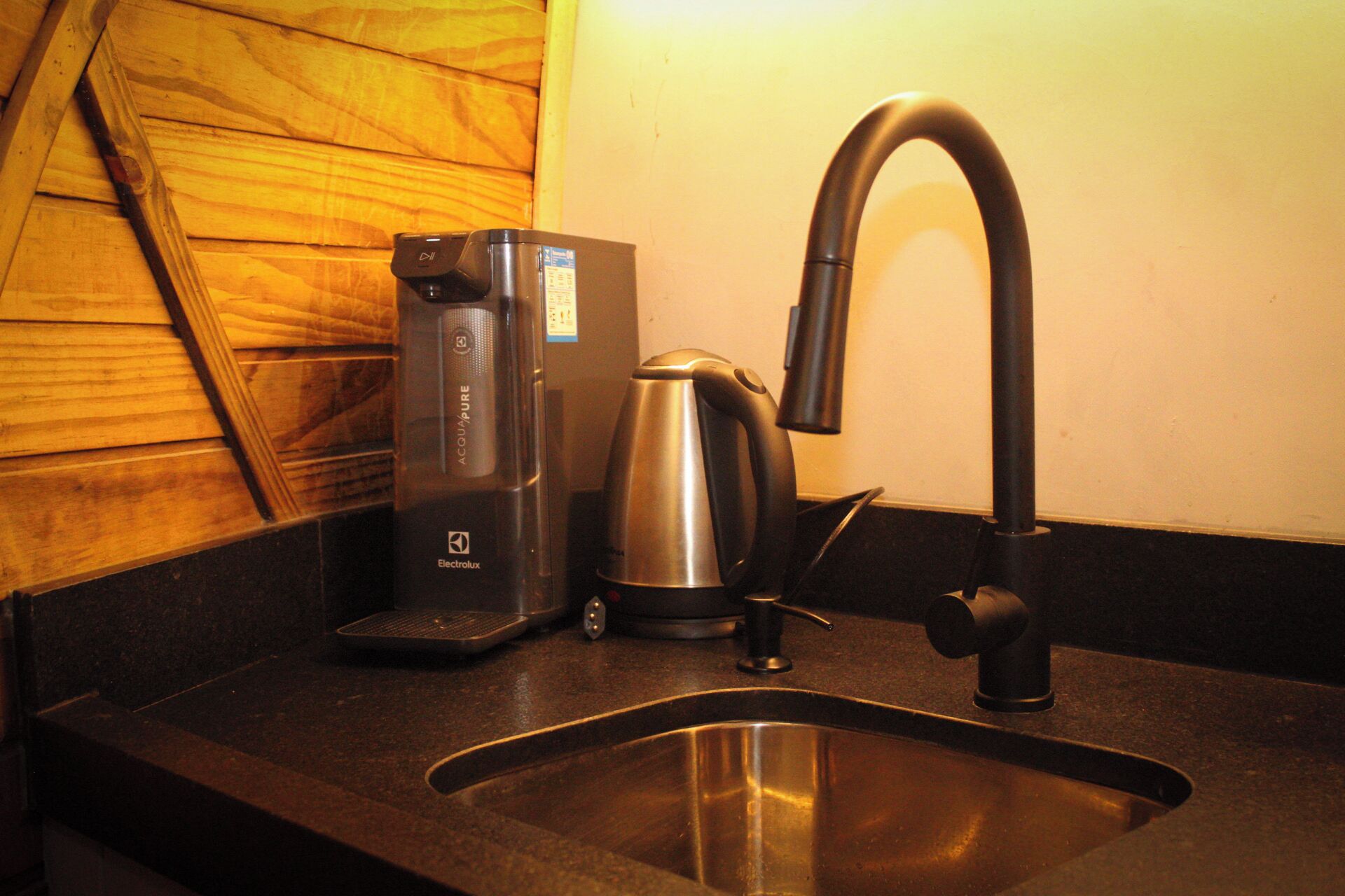 Une cuisine équipée d’une machine à café, d’une bouilloire et d’un robinet moderne.