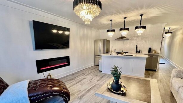 A modern living room with a leather sofa, a coffee table, and a TV mounted on the wall. - Luxury City Loft in Gainesville B (Gainesville)