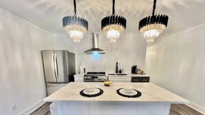 A modern kitchen with a central island, stainless steel appliances, and a chandelier. - Luxury City Loft in Gainesville B (Gainesville)