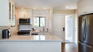 A modern kitchen with white cabinetry, a stainless steel refrigerator, a built-in oven, and a coffee maker. - Napa Golf Course Condo - 2 King Suites + En-Suite Baths - Perfect for 2 couples (Napa)