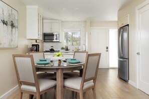 A modern kitchen with white cabinetry, a stainless steel refrigerator, and a dining area with a round table and chairs. - Napa Golf Course Condo - 2 King Suites + En-Suite Baths - Perfect for 2 couples (Napa)