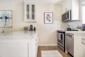 A modern kitchen with white cabinetry, a stainless steel range, and a microwave.
