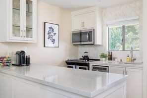 A modern kitchen with white cabinetry, a stainless steel microwave, a kettle, and a coffee machine. - Napa Golf Course Condo - 2 King Suites + En-Suite Baths - Perfect for 2 couples (Napa)
