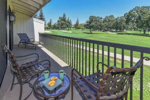 A balcony with wicker chairs, a table with croissants and coffee, and a view of a golf course. - Napa Golf Course Condo - 2 King Suites + En-Suite Baths - Perfect for 2 couples (Napa)