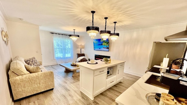 A modern living room with a sofa, a dining table, and a kitchen area with a white island. - Luxury City Loft in Gainesville D (Gainesville)
