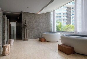 Relax in a serene space with a circular lounge, water feature, and city views through large windows.