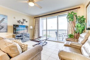 A living room with a sofa, a coffee table, a TV, and a balcony with a view of the water. - Lake view condo! Near Disney! (Orlando)