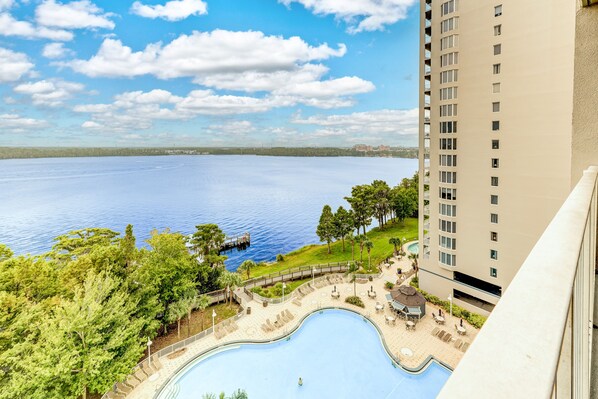 A high-rise building with a swimming pool and a view of a large body of water. - Lake view condo! Near Disney! (Orlando)