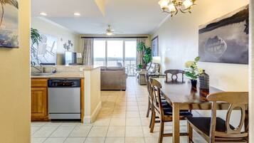 A spacious living area with a dining table, chairs, and a kitchen area with a dishwasher.